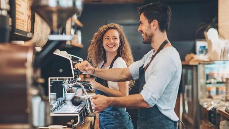 two coffee baristas work in a coffee shop