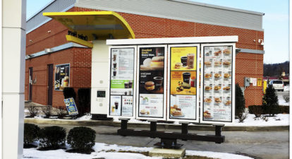 Image of a McDonald's drive-thru with a menu on a screen.