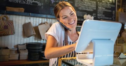 Female cafe owner using a tablet while talking on the phone.